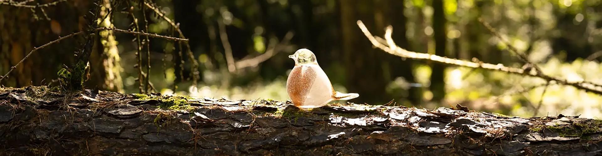 Glazen vogel op boomstam